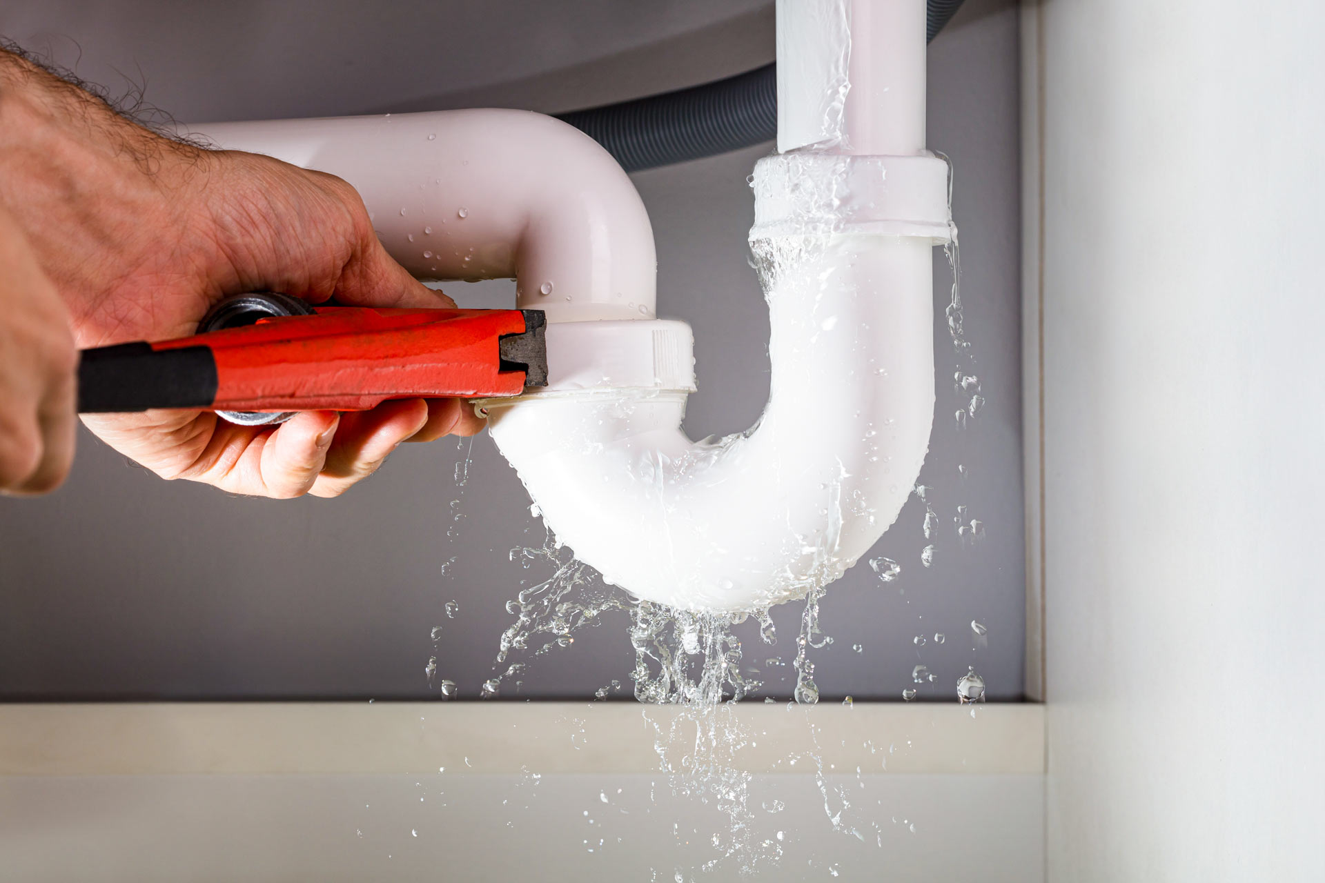 stock-photo-close-up-of-male-plumber-fixing-white-sink-pipe-with-adjustable-wrench-792866032.jpg